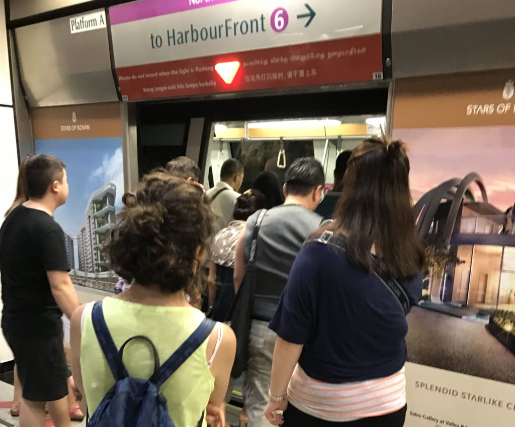 Metro istasyonunda bekleyen insanların arkalarında çekilmiş görüntüsü.