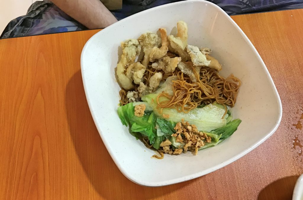 Yemek masasında noodle ve yeşilliklerinolduğu bir yemek tabağından görüntü.