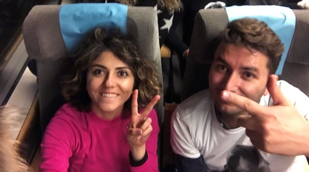 Tren koltuğunda gülümseyip poz veren çiftin görüntüsü.