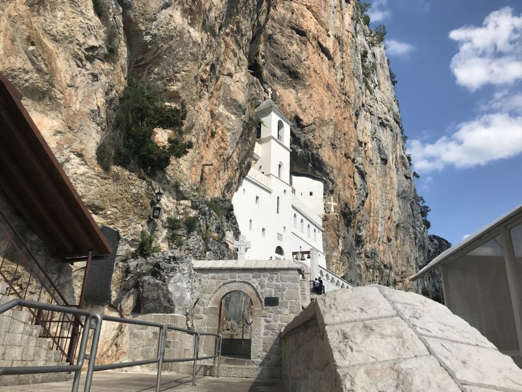 Dağın yamacına krem rengi taşlardan inşa edilmiş manastırın görüntüsü.
