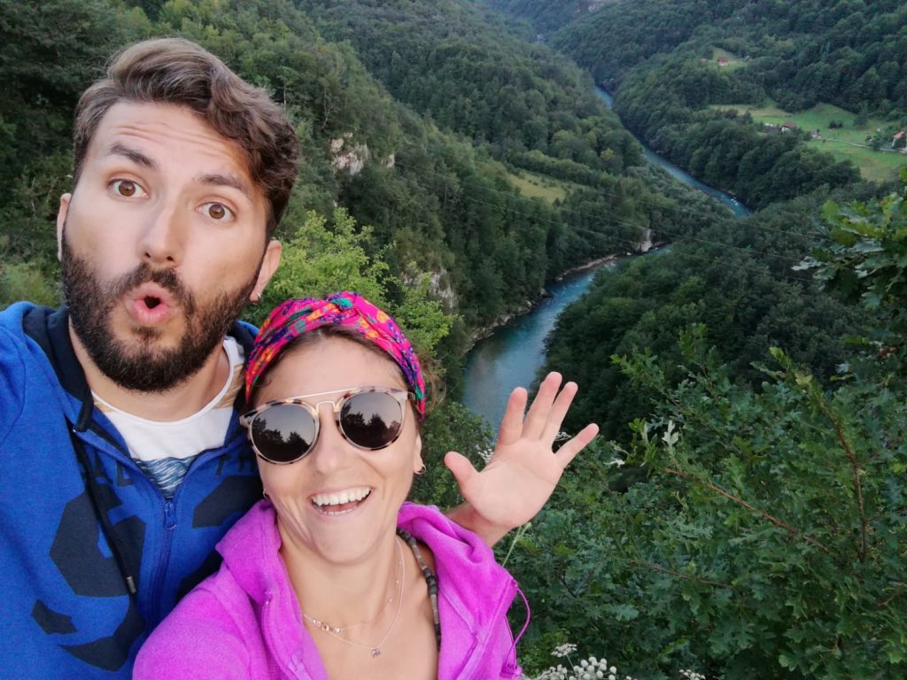 Gezgin bir çiftin arkalarında orman ve nehrin yer aldığı gezi fotoğrafı.