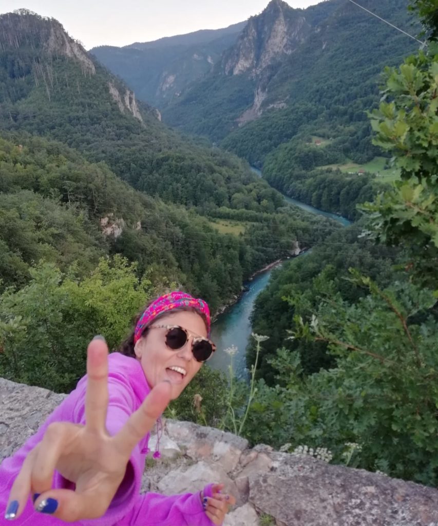 Eliyle zafer işareti yapıp, arkasında muhteşem bir orman manzarası ve Tara Nehri ile poz veren gezginstar.