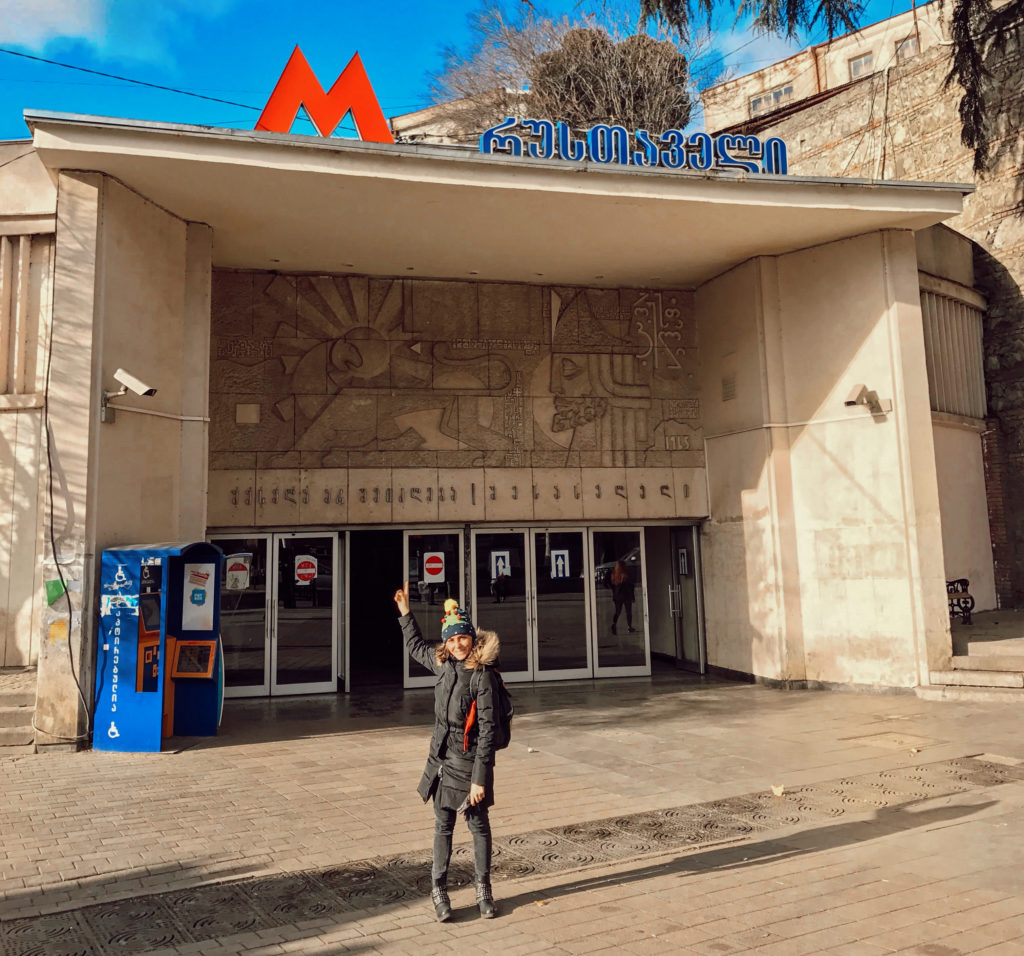 Metroya giriş yapısında poz veren bir kadın görüntüsü.