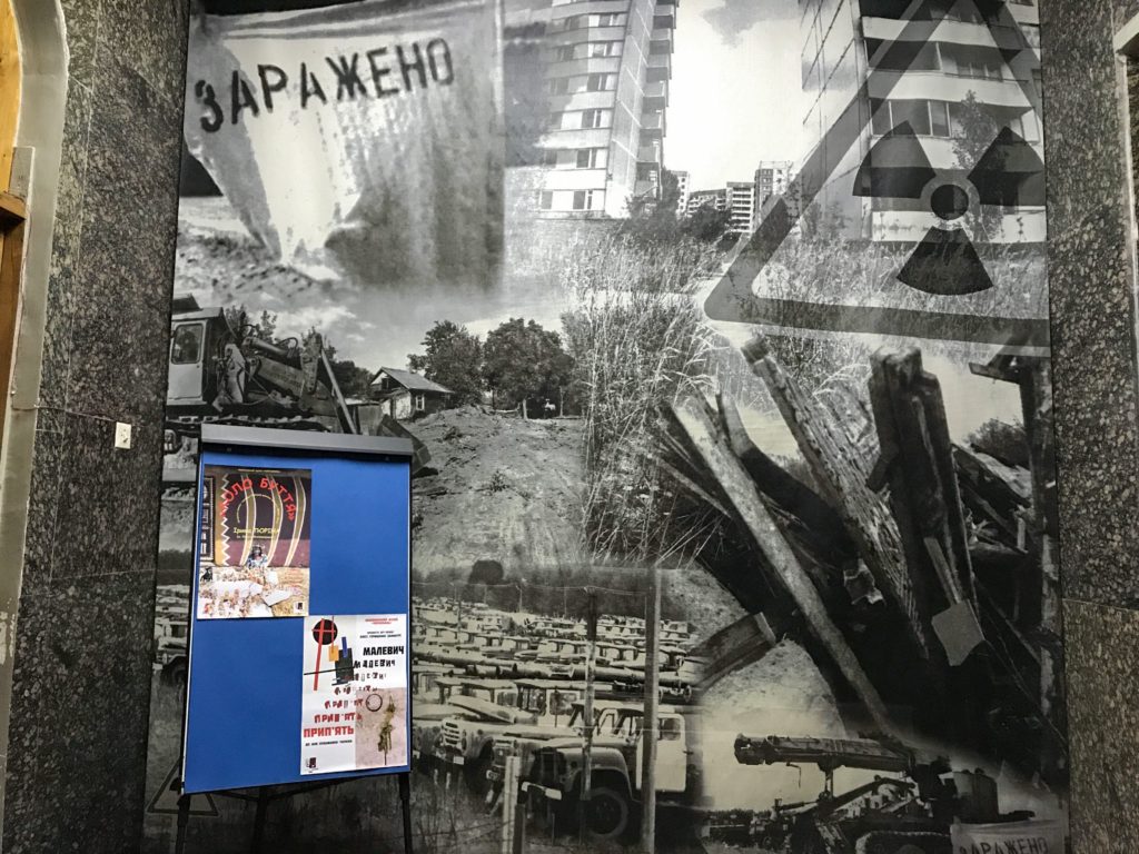Duvarda asılı oldukça büyük siyah, beyaz bir fotoğraf ve fotğraf üzerinde Çernobil Nükleer Santralinde yaşanan kazanın görüntüleri.