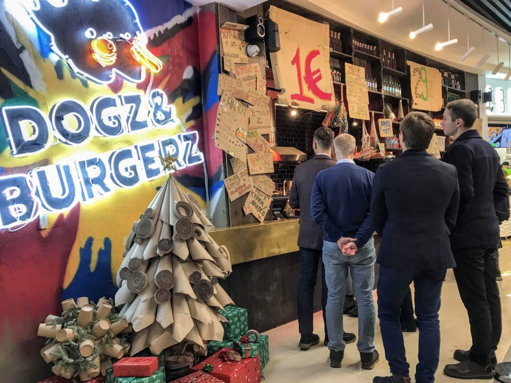 Duvarda Dogz & Burgerz yazısı ve restoran önünde bekleyen insanların yer aldığı görüntü.