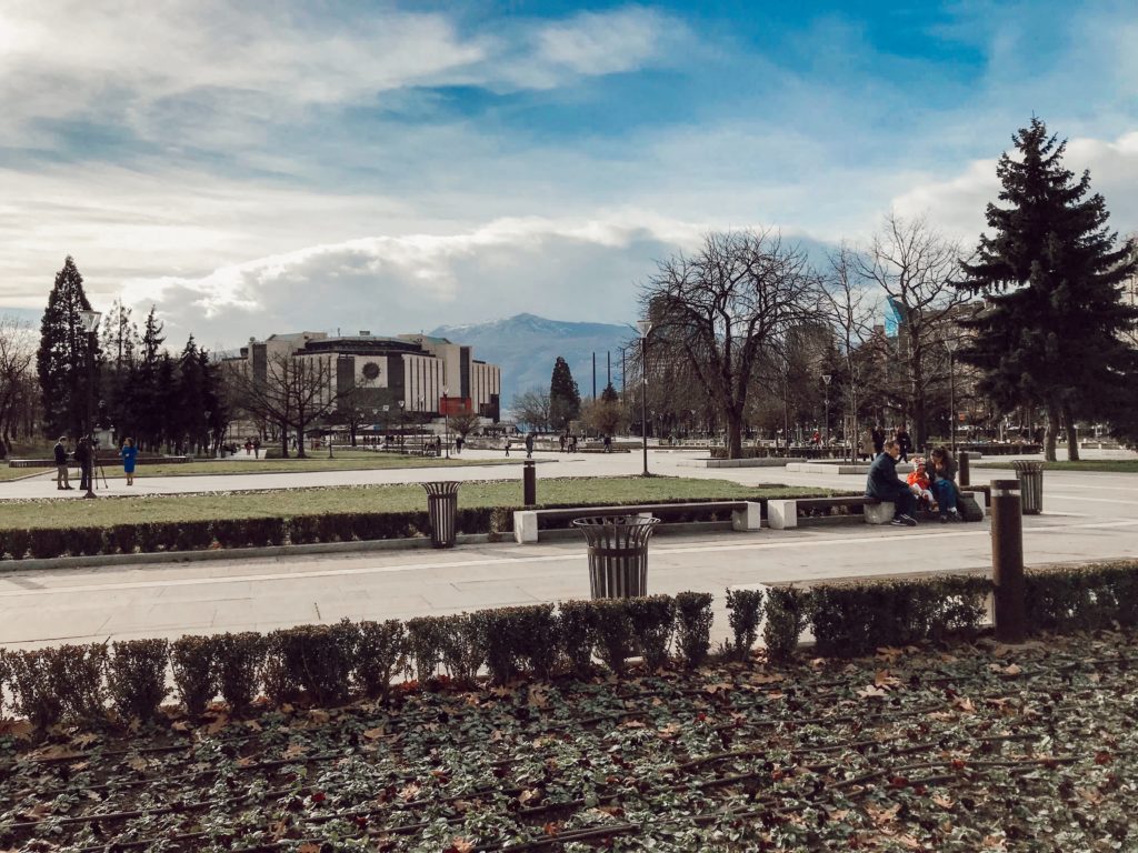 Park içerisinde yürüyen ,oturan insanlar ile uzaklardan görünen Vitosha Dağının manzarası.
