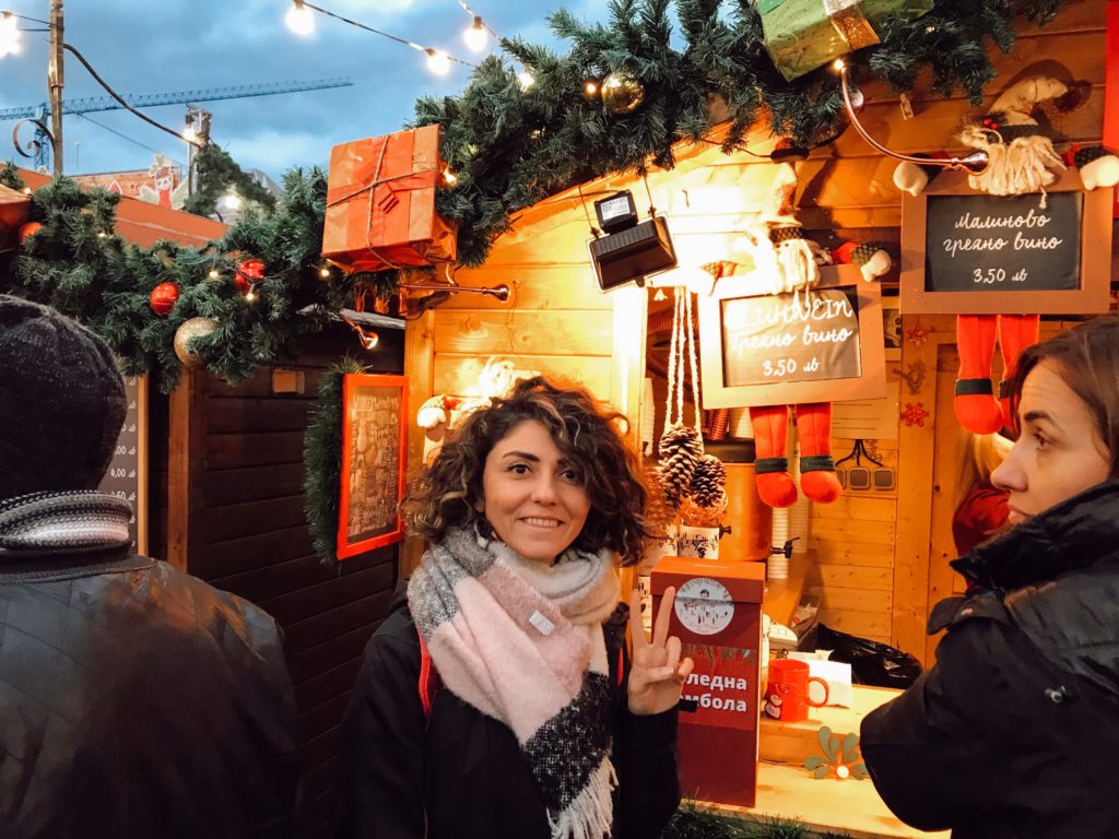 Yılbaşı süsleriyle dekore edilmiş,tahta kulube önünde gülümseyip poz veren GezginStar.