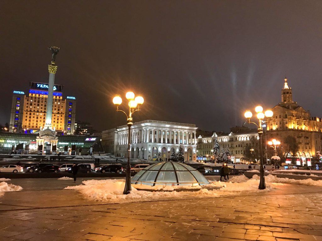 Akşam karanlıkta, ışıklarla aydınlatılan binalar ve sokak lambalarının yer aldığı Kiev gezi rehberi yazısından bir görüntü.