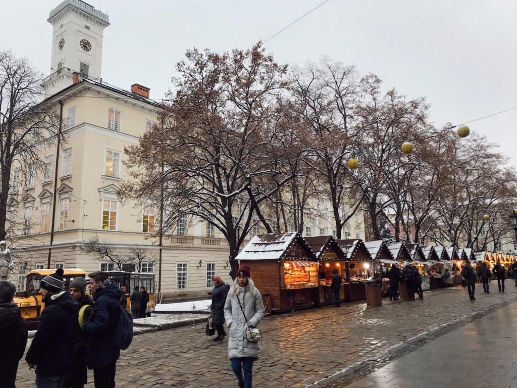 Ahşap yılbaşı kulübeleri, yürüyen insanların yer aldığı Lviv gezi rehberi yazısından bir görüntü.